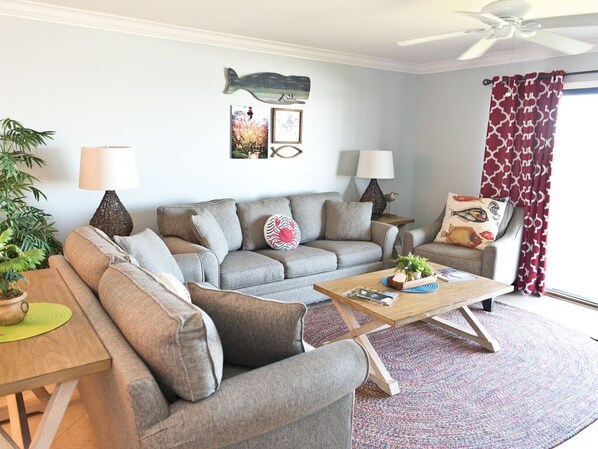 A living room with a grey sofa, two side tables with lamps, a wooden coffee table, and a patterned rug.