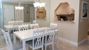 A dining area with white furniture and a kitchen with a built-in oven. - Oceanfront 2 Bedroom Townhouse.  Summerhouse Unit 357 (ST. AUGUSTINE)