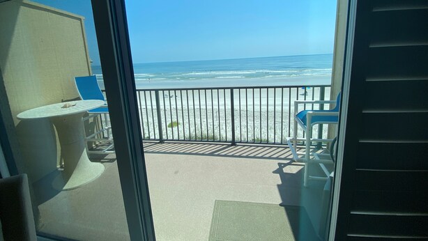 A balcony with a view of the beach and ocean.