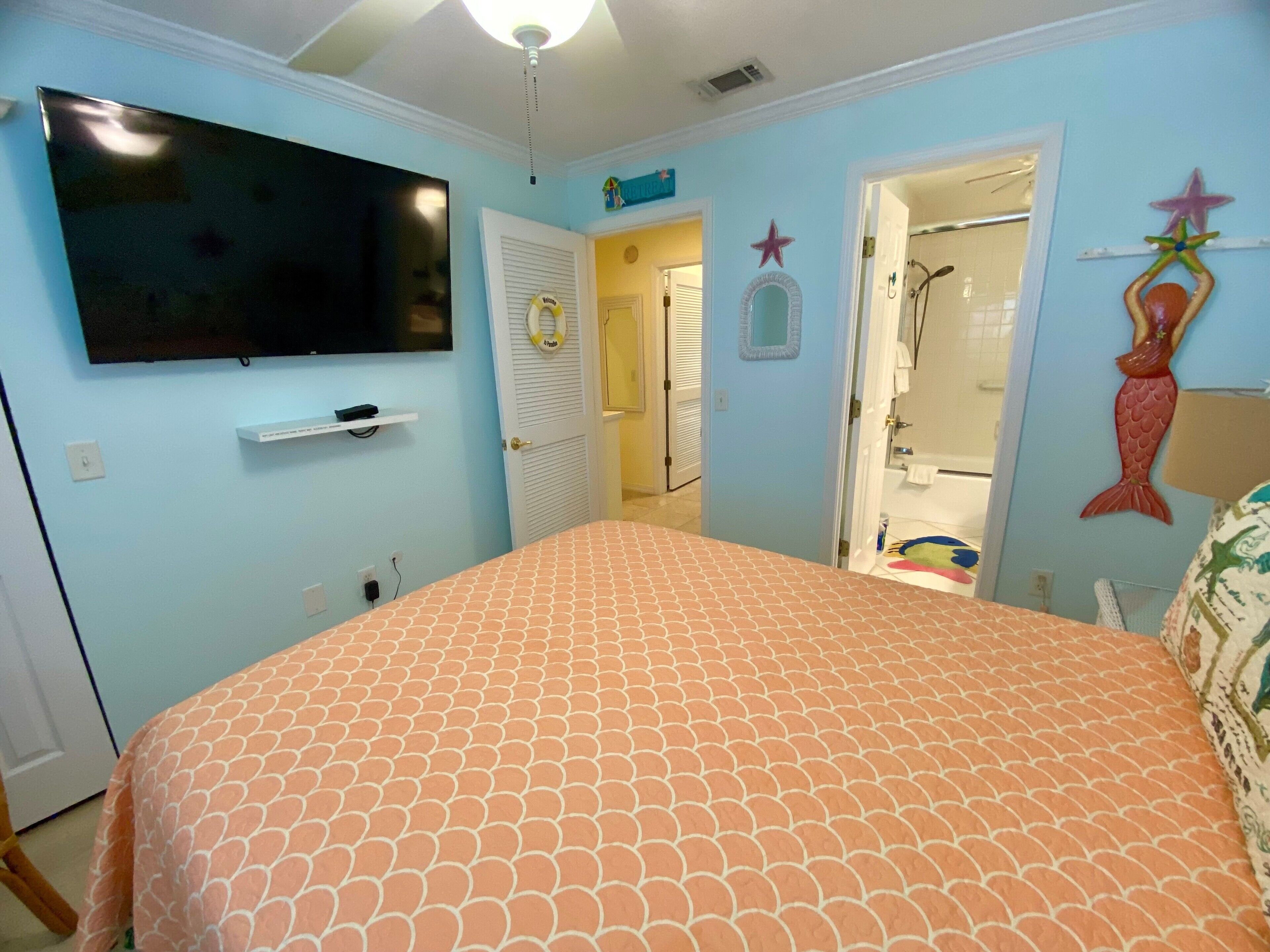 Une chambre avec un lit, une télévision, une porte de salle de bain et un espace douche.
