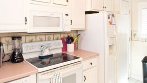 A kitchen with white cabinets, a microwave, a stove, a refrigerator, and a dishwasher.