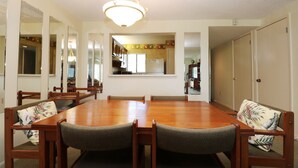 Une salle à manger avec une grande table en bois, plusieurs chaises et un lustre.