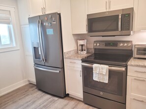 Una cocina moderna con un refrigerador de acero inoxidable, un microondas, un horno y una cafetera.