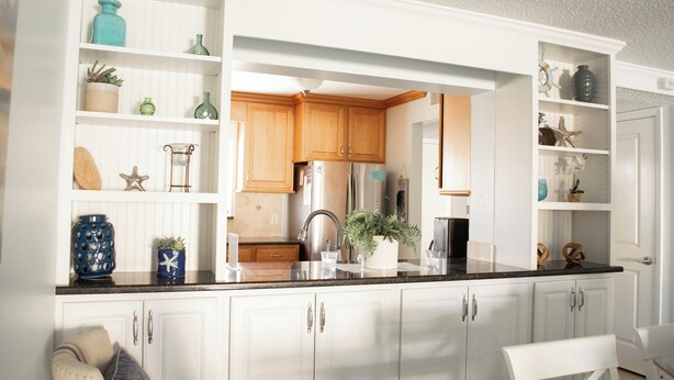 A kitchen with white cabinets, a black countertop, and various decorative items on shelves.