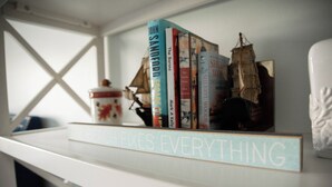 A bookshelf with books and a decorative ship model.