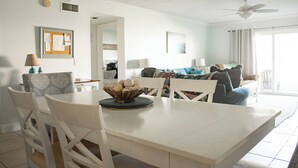 A dining area with a white table and chairs, a bowl of bread, and a ceiling fan.