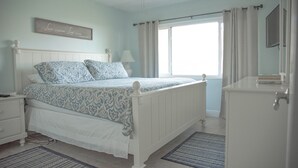 A bedroom with a bed, nightstand, dresser, and a ceiling fan.