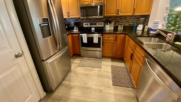 A modern kitchen with stainless steel appliances, wooden cabinets, and a black countertop. - Oceanview 2 Bedroom Flat  Summerhouse 446 (ST. AUGUSTINE)
