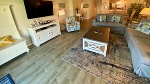 A living room with a flat-screen TV, white entertainment unit, grey sofa, and a coffee table. - Oceanview 2 Bedroom Flat  Summerhouse 446 (ST. AUGUSTINE)