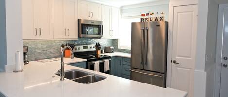 A modern kitchen with white cabinets, stainless steel appliances, and a tiled backsplash.