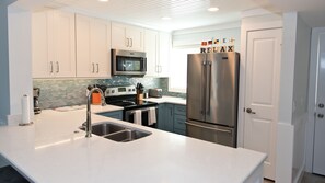 A modern kitchen with white cabinets, stainless steel appliances, and a tiled backsplash.