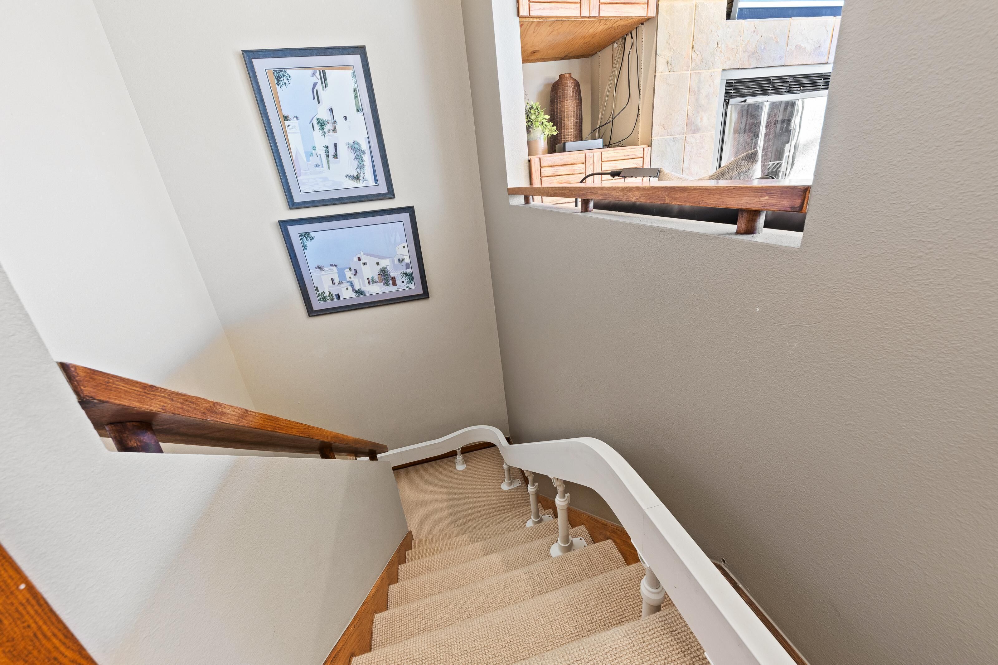 Una escalera con barandilla de madera y alfombra color crema.