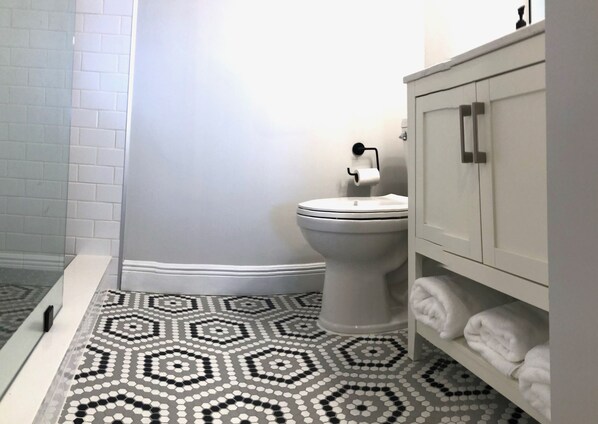 Une salle de bain équipée de toilettes, d’un lavabo et d’un meuble contenant des serviettes.