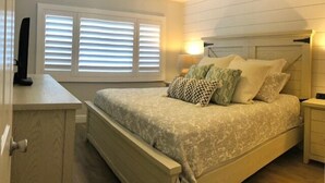 A bedroom with a bed, bedside tables, a ceiling fan, and a window with blinds. - Oceanfront 2 Bedroom Flat  Summerhouse Unit  452 (ST. AUGUSTINE)