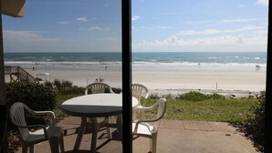 Eine Terrasse mit Tisch und Stühlen mit Blick auf einen Strand.