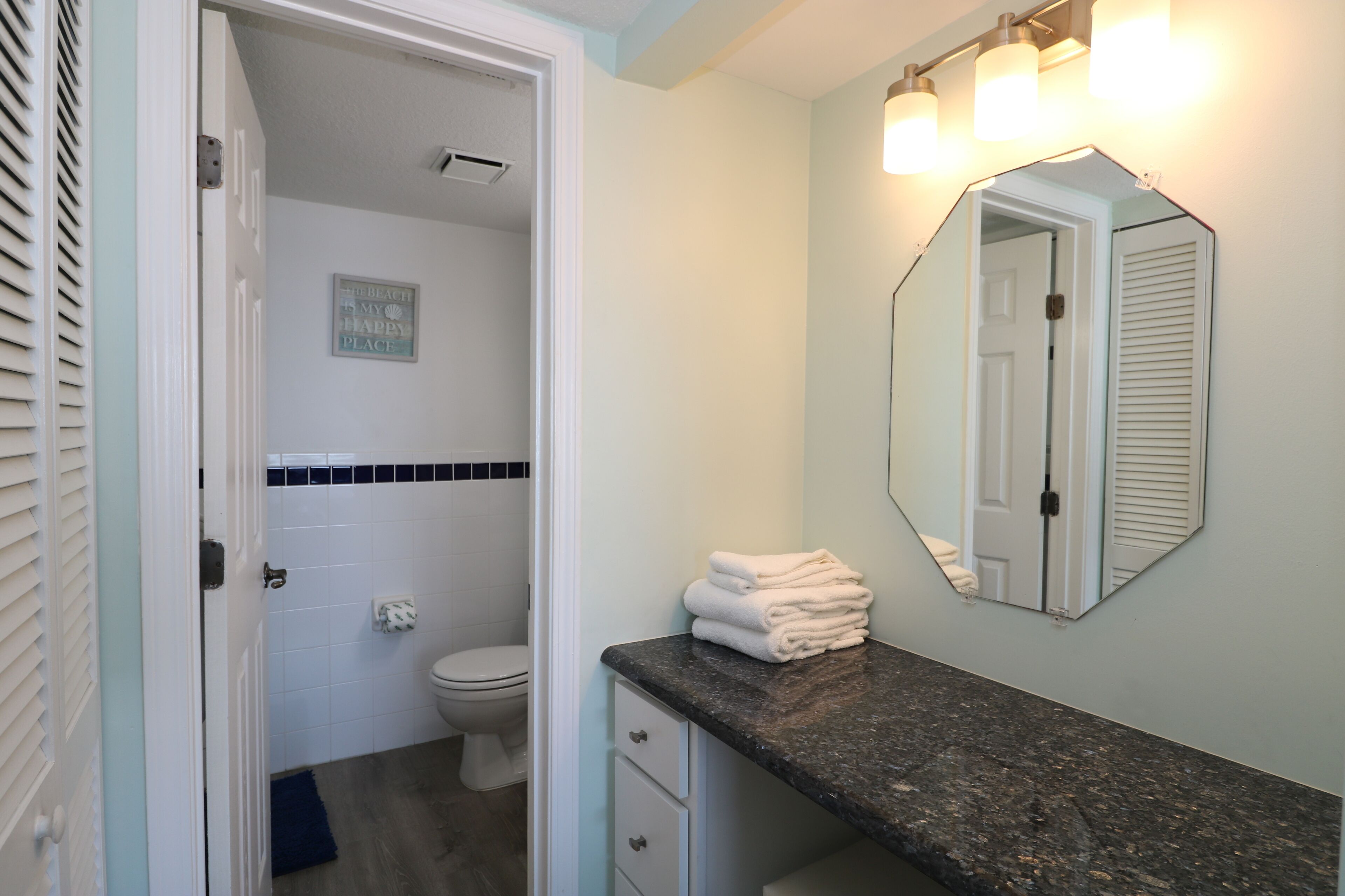 Une salle de bain avec des toilettes, un lavabo avec un miroir et une pile de serviettes.