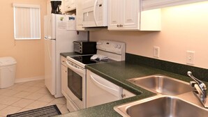 A compact kitchen with white cabinets, a microwave, a toaster, and a dishwasher. - Oceanfront 2 Bedroom Townhouse  Summerhouse Unit 456 (ST. AUGUSTINE)
