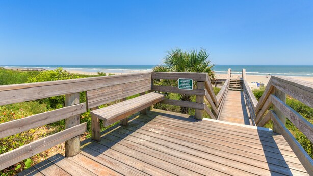 A wooden boardwalk leading to a beach with a sign warning about alcohol.