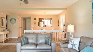 A living room with a grey sofa, a coffee table, and a dining area with a white table and chairs.