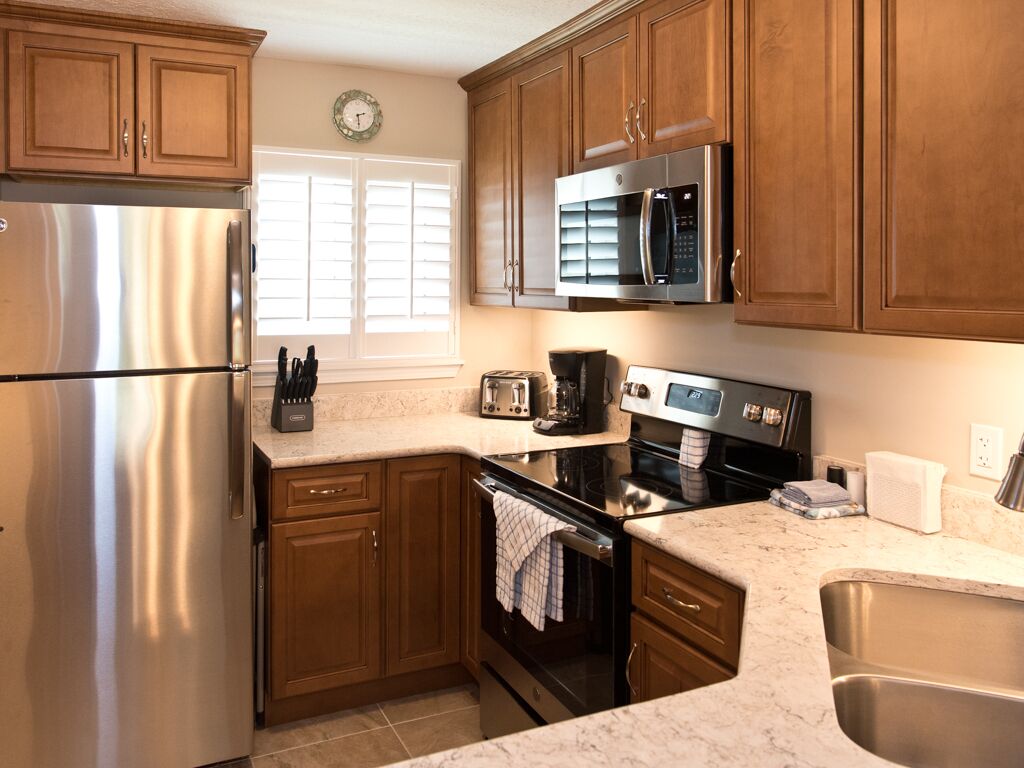 A kitchen with wooden cabinets, stainless steel appliances, a microwave, a toaster, and a sink.