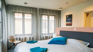 Ein Hotelzimmer mit einem großen Bett, zwei Kissen, einem Sessel und einem Bild an der Wand.