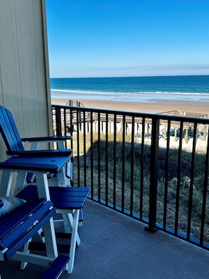 Ein Balkon mit blauen Stühlen und Blick auf den Strand.