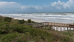 A wooden pier extending into the ocean with a sandy beach and greenery in the foreground. - Beautiful Direct Oceanfront 2 bed 2.5 bath Townhouse- Summerhouse 162 (St. Augustine)