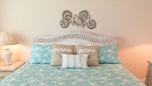 Un letto con copriletto a motivi blu e bianchi a stelle, due cuscini con la scritta 'ocean' e una decorazione murale raffigurante una bicicletta.