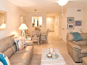 A living room with two sofas, a dining table with chairs, a lamp, and a rug.
