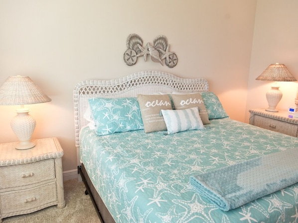 A bedroom with a bed, two nightstands, and decorative wall art.