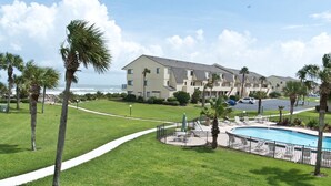 Un hotel con piscina, palme e vista sull'oceano.