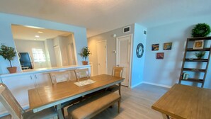 A dining area with a wooden table and benches, a kitchen in the background, and a mirror on the wall. - Don't miss this direct Oceanfront view at the beloved Summerhouse 254 (St. Augustine)