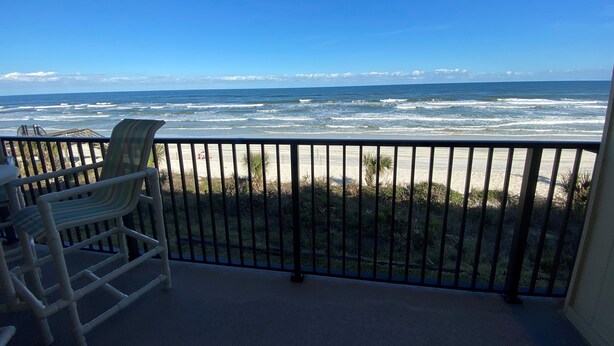 A balcony with a view of the ocean, a chair, and a table. - Don't miss this direct Oceanfront view at the beloved Summerhouse 254 (St. Augustine)