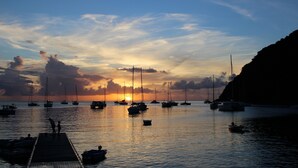Un port de plaisance avec des bateaux amarrés à un quai en bois, au coucher du soleil.