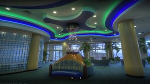Eine Lobby mit einer gebogenen Sitzgruppe, großen Fenstern und einem Chandelier.