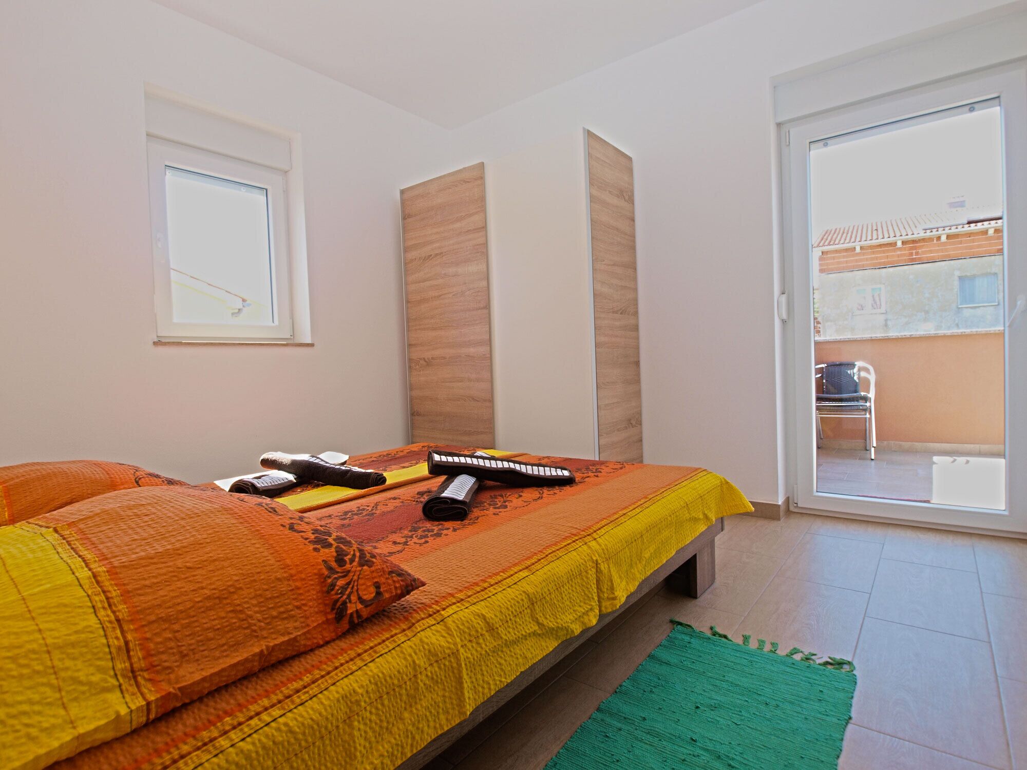 Una camera da letto con un letto, cuscini, un telecomando e un tappeto verde.