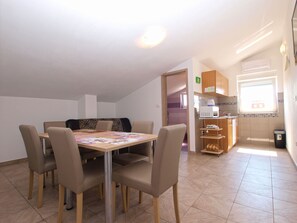 A dining area with a table and chairs, a kitchenette, and a window. - Apartment 1480/13828 (Istria - Liznjan), 800m from the beach (Liznjan)