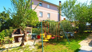 A backyard with a swing set, a barbecue grill, and a table with chairs.