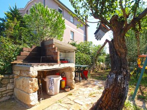 An outdoor stone structure with a grill, a fire extinguisher, and a table with chairs. - Apartment 1480/13828 (Istria - Liznjan), 800m from the beach (Liznjan)