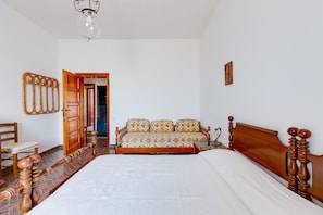 A bedroom with a large bed, wooden headboard, a bedside table, a chair, and a wardrobe. - Villa Timbora on the Beach with Ocean View, Terrace (Cabras)