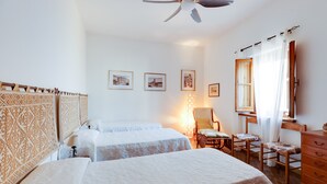 A hotel room with two beds, a ceiling fan, a wooden dresser, a chair, and framed pictures on the wall. - Villa Timbora on the Beach with Ocean View, Terrace (Cabras)