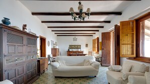 A room with a patterned floor, a white sofa, wooden furniture, and a chandelier. - Villa Timbora on the Beach with Ocean View, Terrace (Cabras)