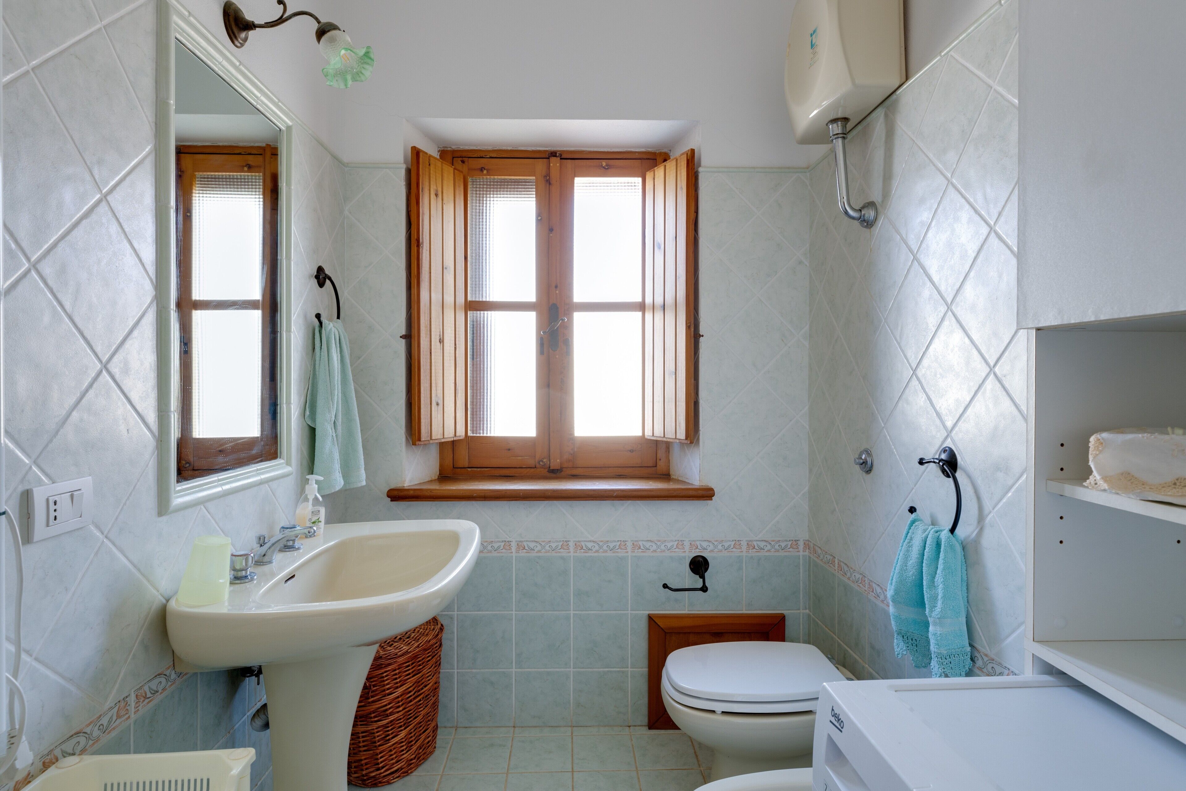 Een badkamer met een wastafel, toilet en raam.