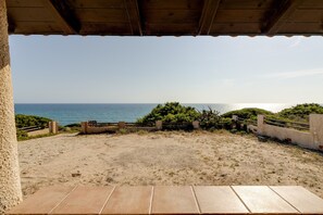 Une vue sur la plage depuis un espace abrité, avec un premier plan sablonneux et un ciel bleu dégagé.