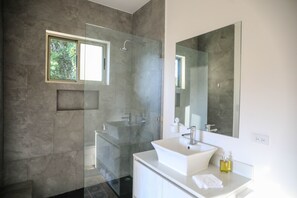 A modern bathroom with a glass-enclosed shower, a white sink, and a large mirror.