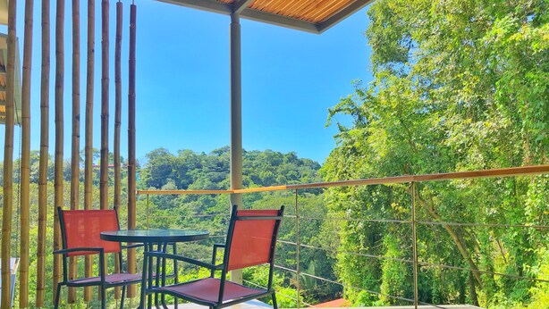 Ein Balkon mit Tisch und Stühlen mit Blick auf einen üppigen grünen Wald.