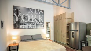 Ein Hotelzimmer mit einem Bett, einem Wandbild von New York City, einem Kühlschrank und Holzschränken.