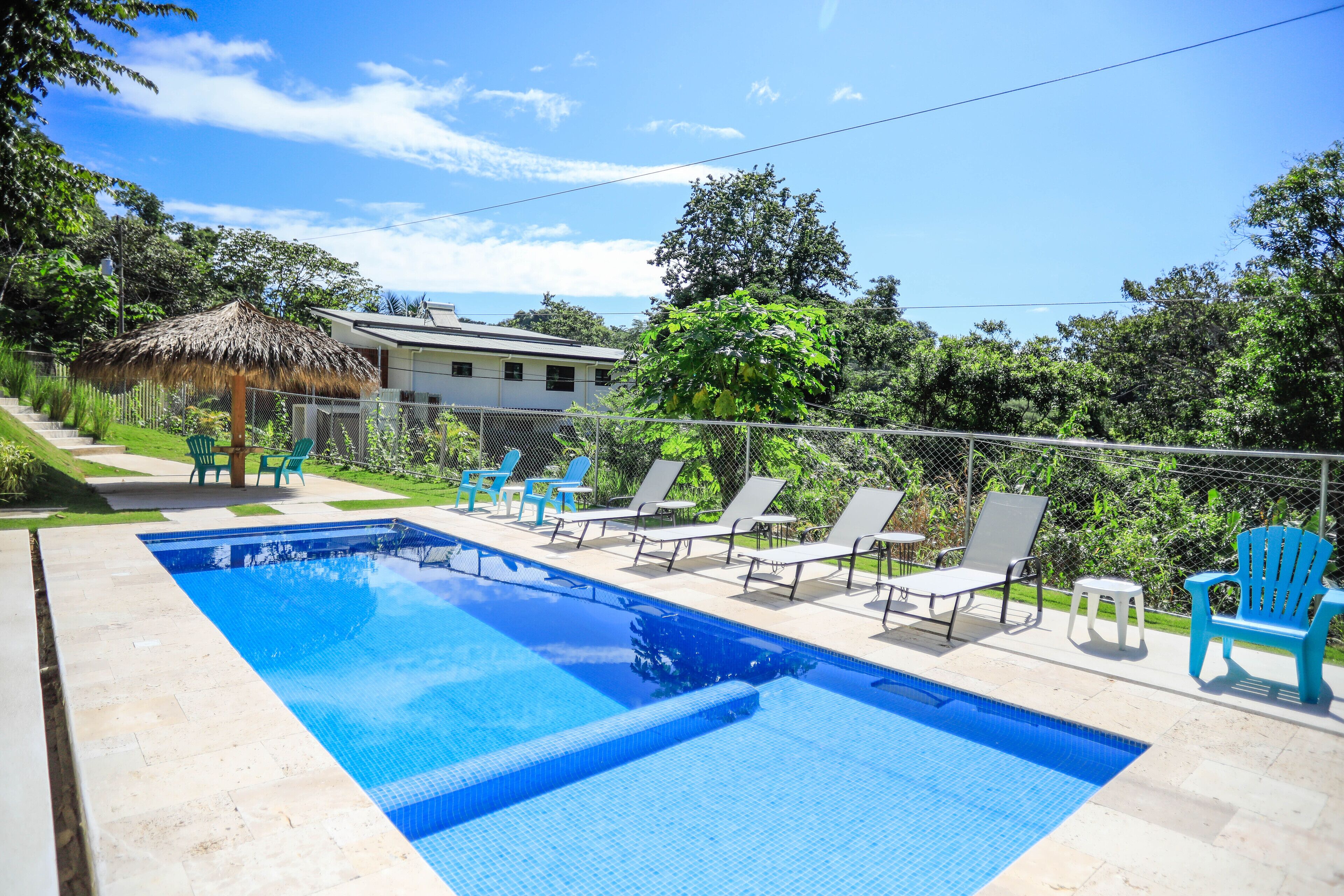 A swimming pool with lounge chairs and a thatched umbrella.