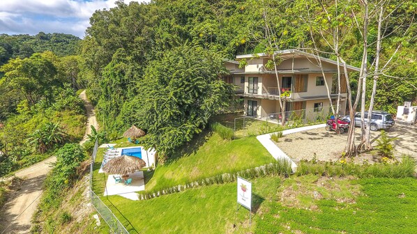 A two-story building with a swimming pool and a thatched-roof structure.