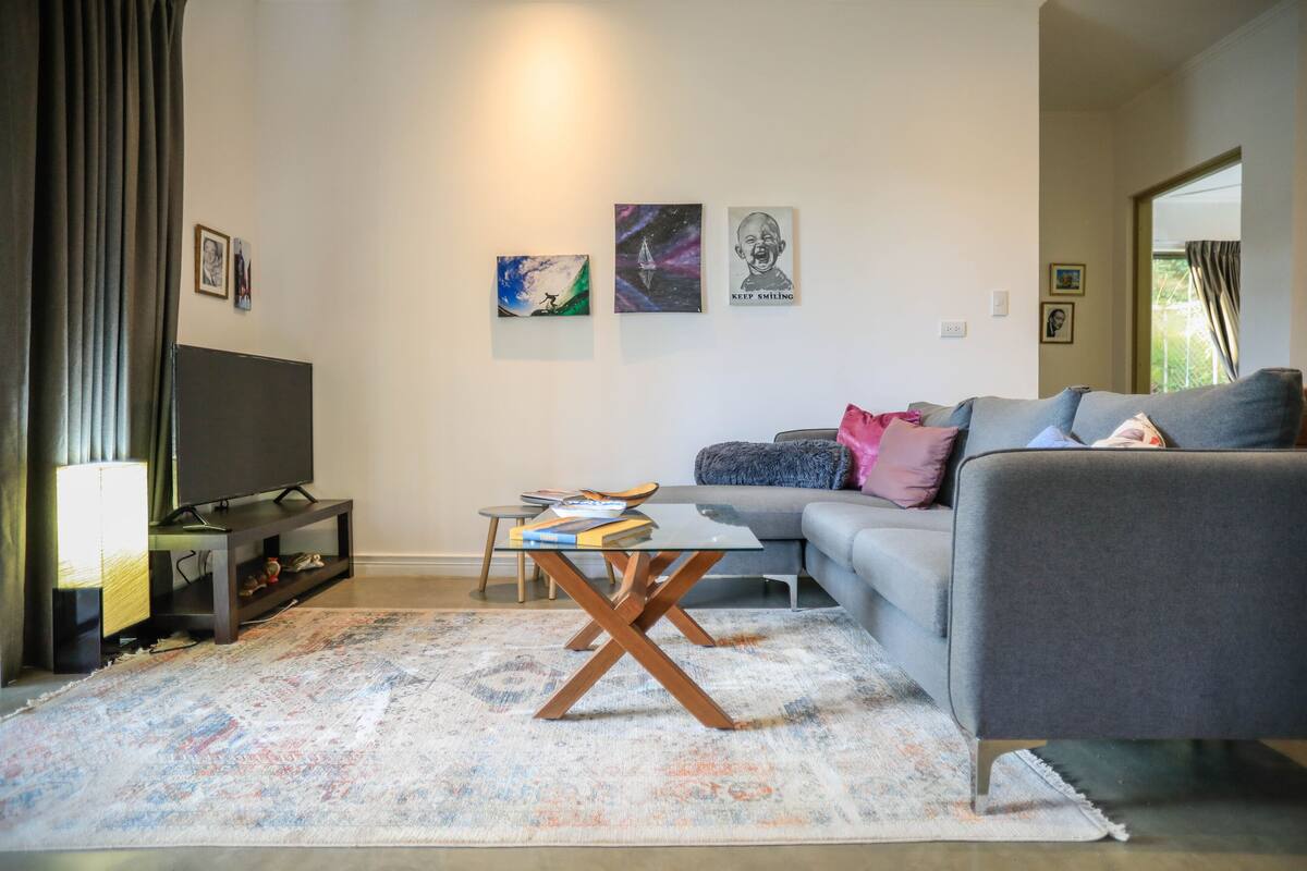Uma sala de estar com sofá, mesa de centro, TV e obras de arte na parede.